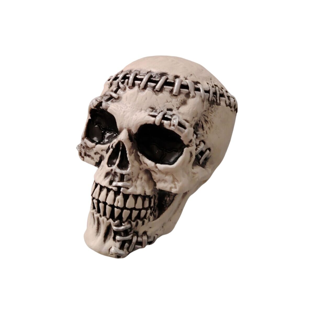 En vit, makaber dekoration av en skalle med sömmar runt huvudet och tomma ögonhålor, fotograferad mot en vit bakgrund.