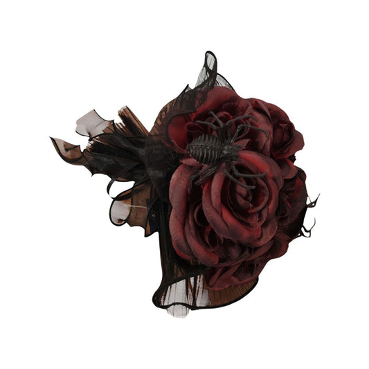 En dekorativ bukett med mörkröda rosor och en svart spindel som sitter på toppen, omgiven av svart tyll och tyg.