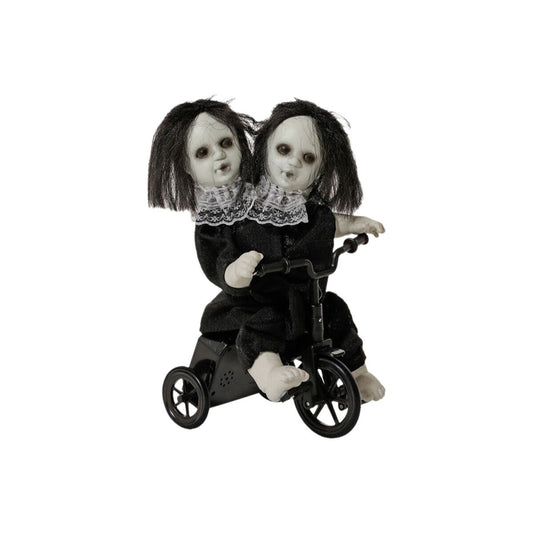 En animerad Halloween-dekoration som visar en docka med två huvuden och svart hår sitta på en liten svart trehjuling.