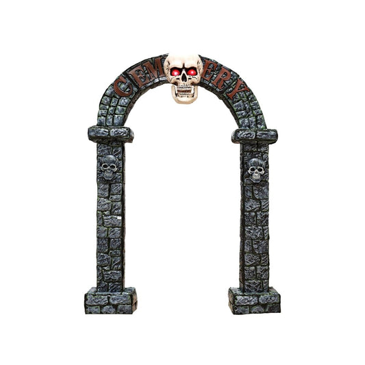 En stor, gråfärgad dekorativ portal i stenlook med texten "Cemetery" (Kyrkogård) över bågen, toppad med ett lysande dödskallehuvud med röda ögon, och mindre dödskallar inbäddade i pelarna.
