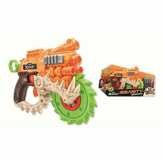 En närbild av en stor, orange leksakspistol med gröna och beiga/vita detaljer som liknar ben, samt ett stort grönt sågblad i fronten. Förpackningen med texten 'XSHOT INSANITY HORRORFIRE' syns vid sidan om.