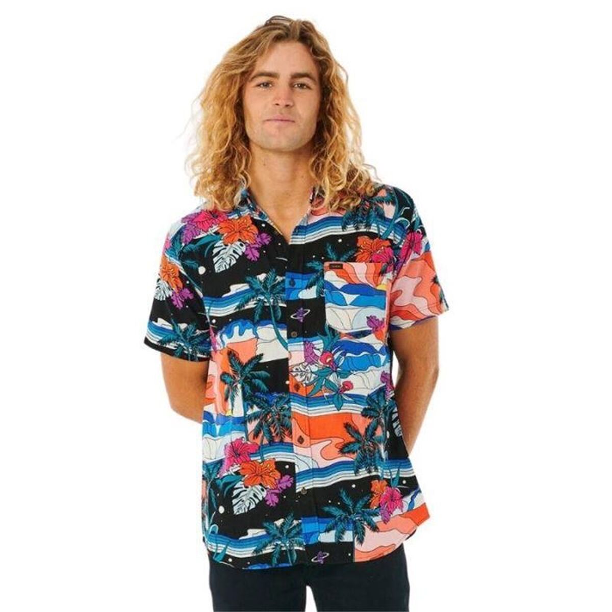 En man med långt lockigt hår bär en färgglad kortärmad hawaiiskjorta med motiv av palmer och blommor.