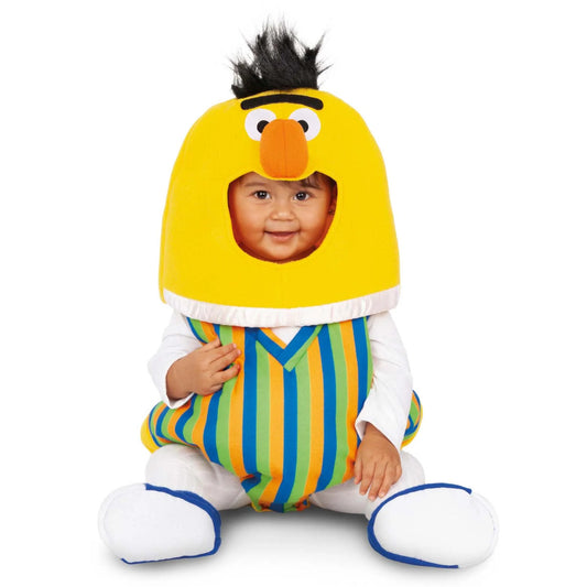 Bebis utklädd till Baby Bert från Sesame Street med gul huvuddel, randig kropp i blått, grönt, gult och orange samt vit dräkt under, sittandes på golvet och ler.