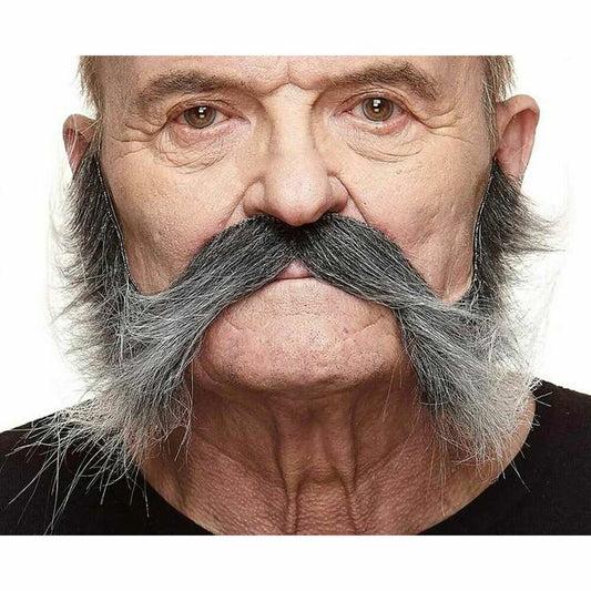 En man bär en mycket stor och yvig, gråtonad lösmustasch med långa, buskiga polisonger, vilket ger en klassisk biker- eller wrestling-look.