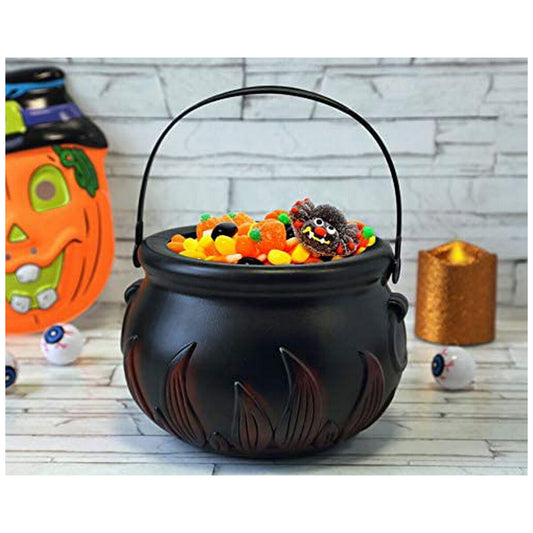Den eldiga svarta häxkitteln fylld med Halloweengodis, placerad på ett bord med andra dekorationer som en pumpa och leksaksögon.