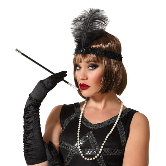 En kvinna i en elegant 20-tals utklädnad som visar upp ett glamour-kit med ett svart fjäder-pannband, ett långt pärlhalsband och ett cigarettmunstycke.