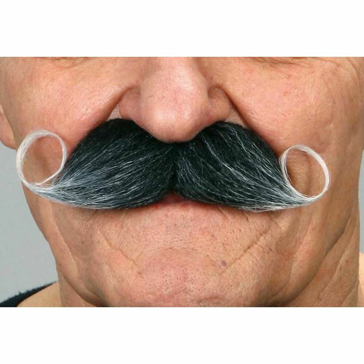 Närbild på en man som bär en stor, svart och gråmelerad mustasch med perfekt upprullade ändar, känd som en hertig-mustasch.