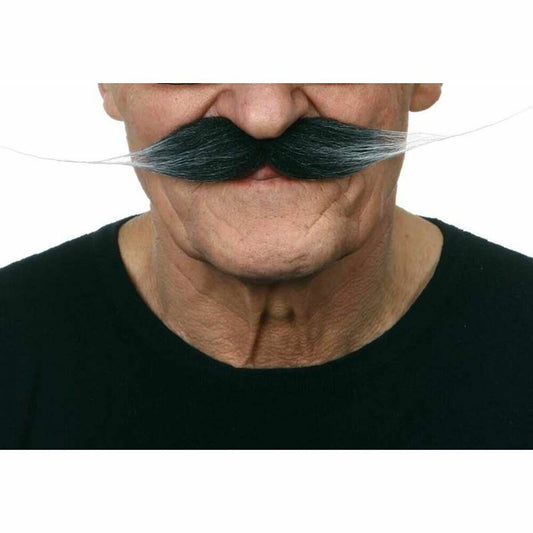 En närbild visar en äldre mans ansikte som bär en tjock, svart mustasch som tonar till grått/vitt i de utsvängda ändarna, en så kallad musketör-mustasch.