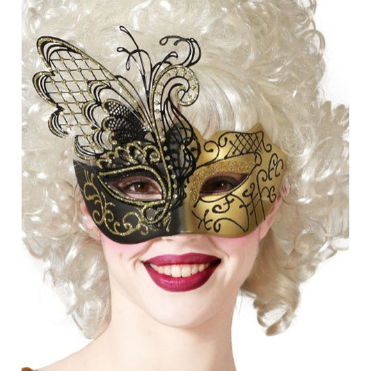 En leende kvinna med en stor, vit peruk bär en elegant och asymmetrisk ögonmask i svart och guld, formad som en fjäril på ena sidan.