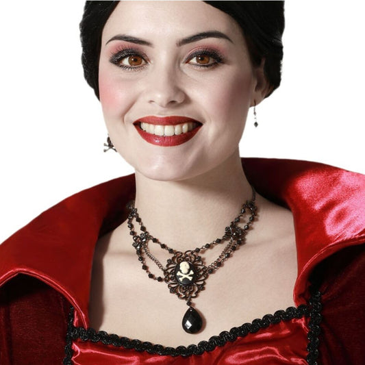 En leende kvinna med vampyr-look bär det Gotiska Smyckessetet med dödskalle-medaljong till en röd och svart klänning.