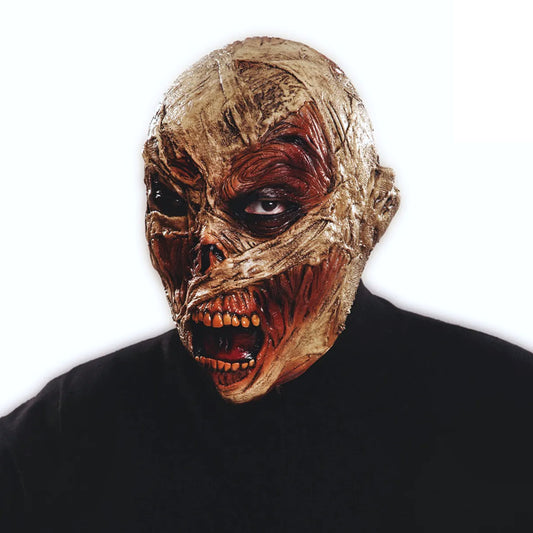 En person bär en superläskig, heltäckande latexmask som ser ut som en ruttnande mumie med blottat rött kött, bandageliknande hud och en öppen mun med hemska tänder.
