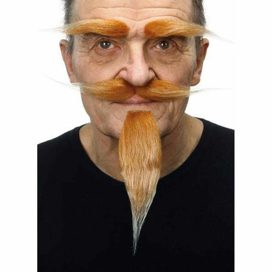 En man bär en orange/blond lösmustasch, ett långt getskägg som tonar i vitt i spetsen, och tjocka, buskiga ögonbryn.