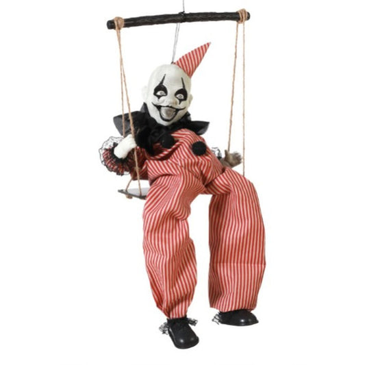 En läskig, gungande clowndekoration i röd- och vitrandiga kläder med ett skrämmande leende sitter på en gunga av rep.
