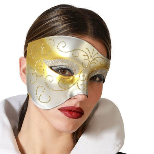 En kvinna med mörkt, uppsatt hår och röda läppar bär en elegant, tvåfärgad ögonmask i guld och silver med snirkliga glittermönster.
