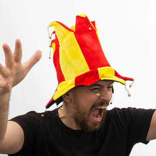 Entusiastisk man med hög jesterhatt i Spaniens färger, jublar med armarna uppåt.