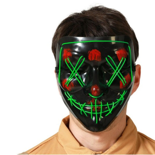 Närbild på en person som bär en svart mask med gröna, lysande LED-trådar och röda blodstänk, för en hotfull The Purge-look.