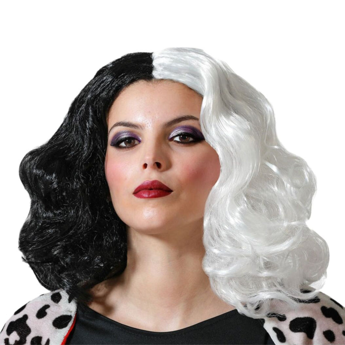 En kvinna med dramatisk makeup bär en ikonisk, axellång peruk som är delad i en svart och en vit halva med stora, eleganta lockar.