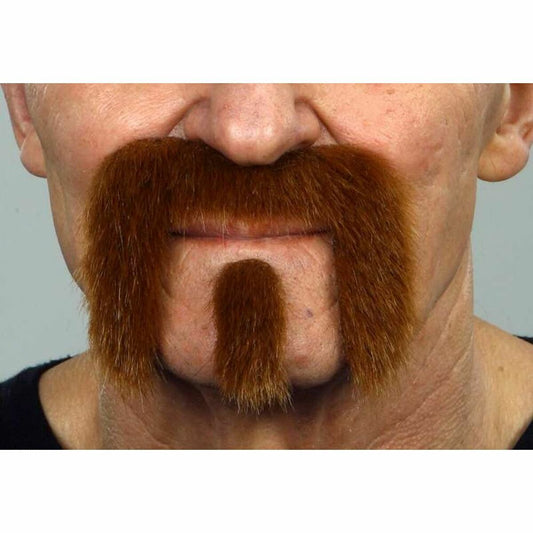 Närbild på en mans ansikte där en kastanjebrun, tjock mustasch och hakskägg i biker/skurk-stil är fastklistrad på huden.