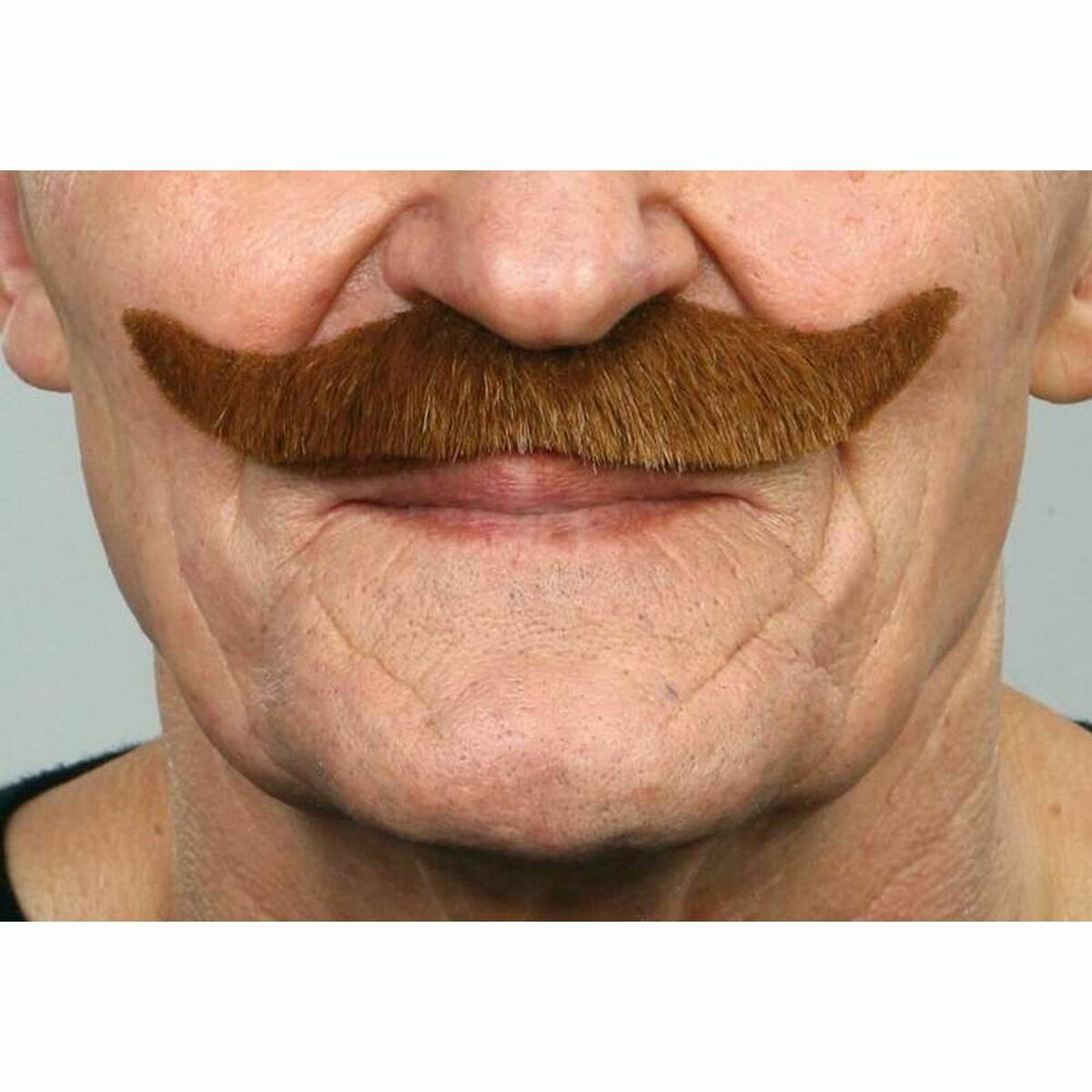 Närbild på en man som bär en tjock, kastanjefärgad mustasch med uppåtsvängda ändar över överläppen.