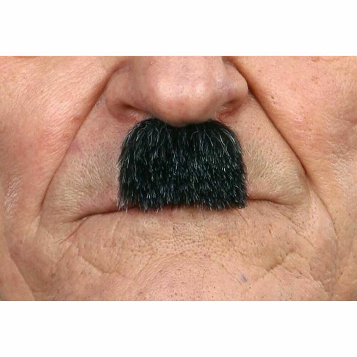 Närbild på en tjock, svart, rektangulär mustasch som är fasttejpad på huden under en persons näsa.