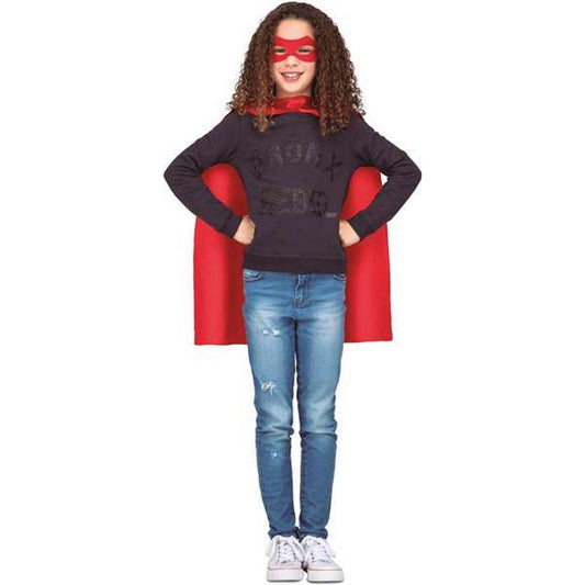 En flicka ler med händerna på höfterna, klädd i det röda superhjälte-kitet med cape och mask.