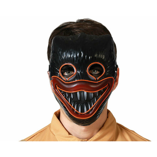 En person bär en kuslig, svart LED-skräckmask med ett stort, läskigt leende som lyser med en orange tråd.