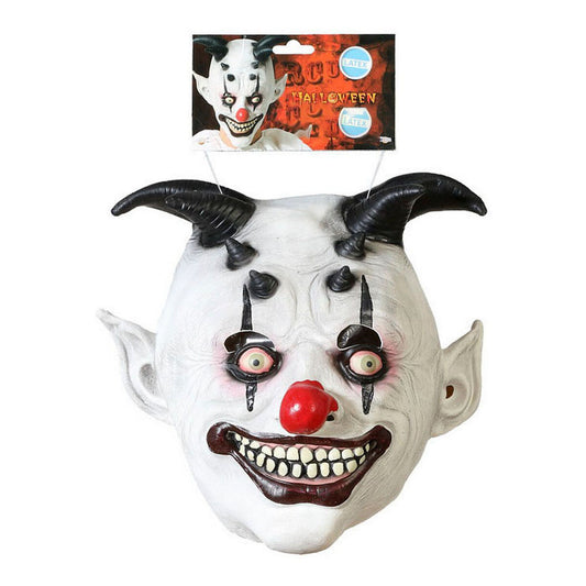 Produktbild av en vit latex halloweenmask föreställande en demonisk clown med svarta horn, spetsiga öron och röd clownnäsa, med skrämmande ögon och bred tandrad, hängande på förpackning med Halloween-etikett.