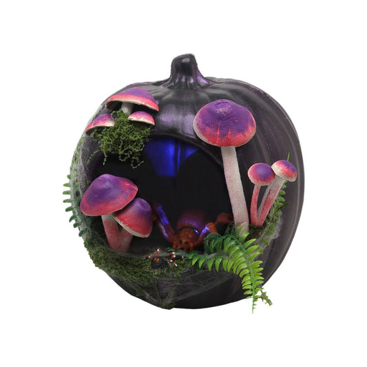 En dekorationspumpa i mörklila färg med ett urholkat hål fyllt av lila och röda svampar, konstgjord mossa och en stor spindel i mitten. Pumpan är dekorerad för halloween med naturinspirerade detaljer.