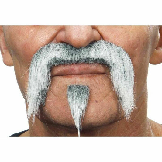 Närbild på en man som bär ett ikoniskt, grått wrestler-set med en stor lössmustasch och ett matchande hakskägg, fotograferad i studio.
