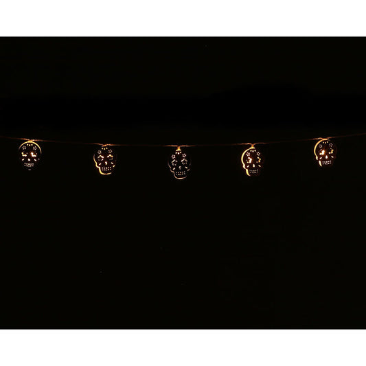 En ljusslinga med utskurna dödskallar som lyser med ett varmt, gult sken i mörkret, perfekt som halloweendekoration.