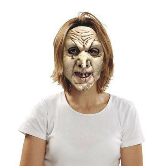 En kvinna med kortare, ljust hår bär en läskig, heltäckande häxmask med rynkor, vårtor och ruttna tänder.