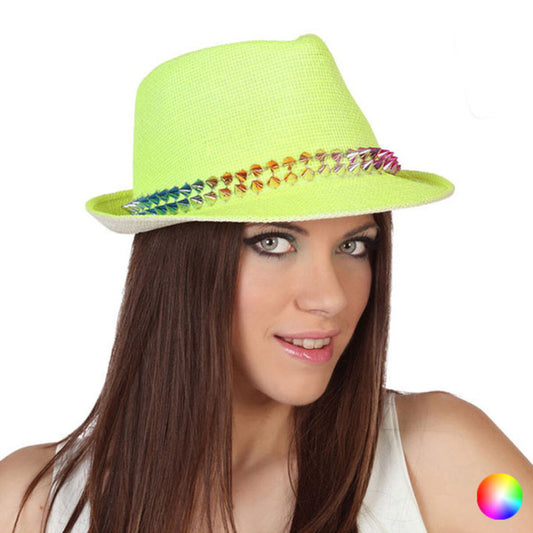 En kvinna med gröna ögon bär en neongul fedora-hatt med ett band av regnbågsfärgade nitar.