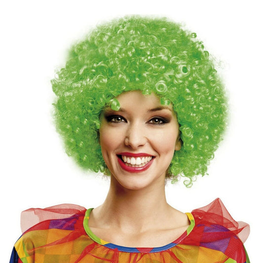 En leende kvinna i en färgglad clowndräkt bär en stor, yvig och superkrullig peruk i en intensiv, neongrön färg.