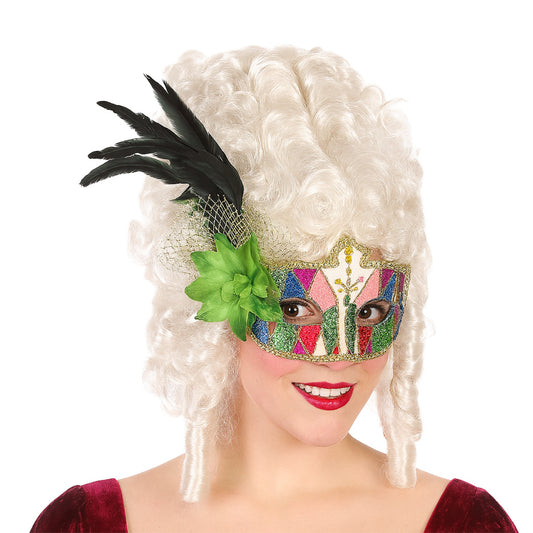 Kvinna med vit peruk bär en glittrig ögonmask i harlekinmönster med grön blomma och svarta fjädrar – perfekt för maskerad eller venetiansk fest.