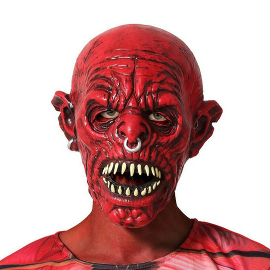 Närbild på en skrämmande röd demonmask med huggtänder och näspiercing, buren av en person i röd dräkt.