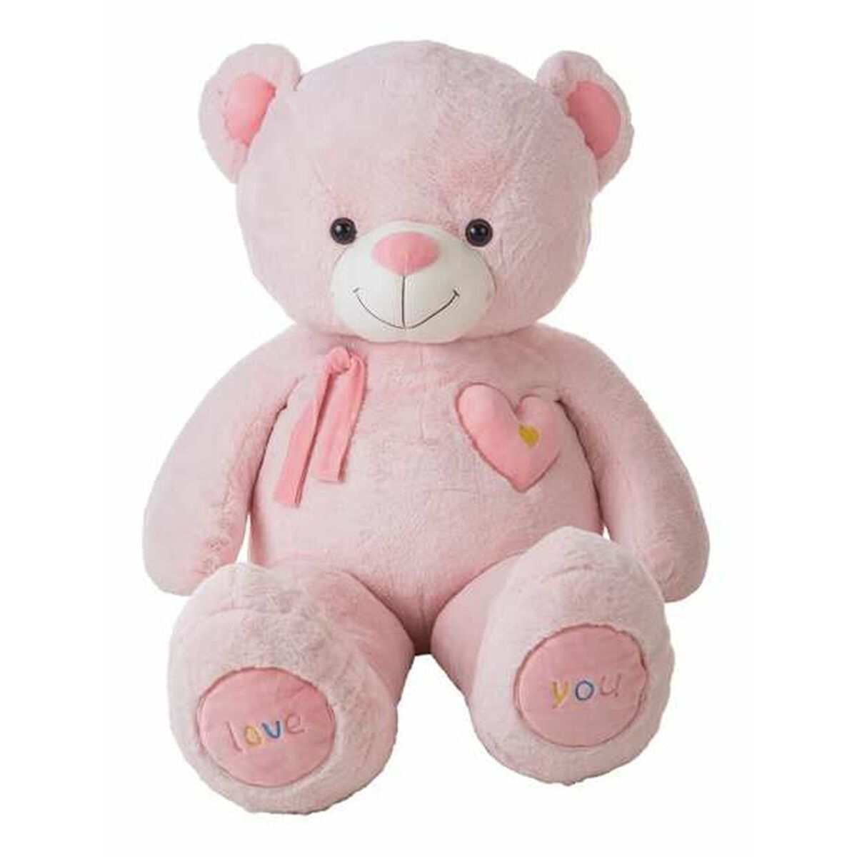 En sittande jättestor rosa teddybjörn med ett rosa hjärta på bröstet och texten love you broderad på fotsulorna mot en vit bakgrund.