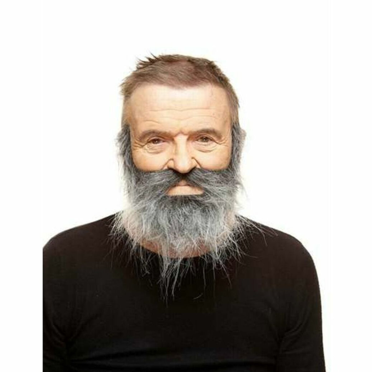 En man bär ett tjockt, rufsigt lösskägg i gråa nyanser som täcker underläpp, haka och kinder.