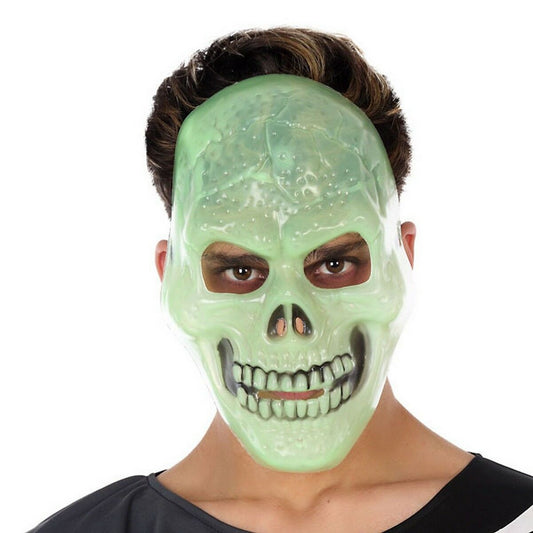 En person bär en ljusgrön, Självlysande Dödskallemask i plast.