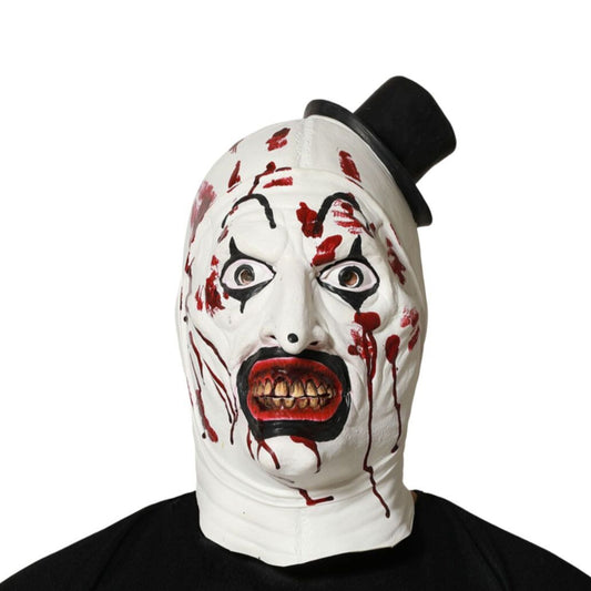 En person bär en skräckinjagande, vit clownmask täckt i blod, med ruttna tänder och en liten svart minihatt på sned.