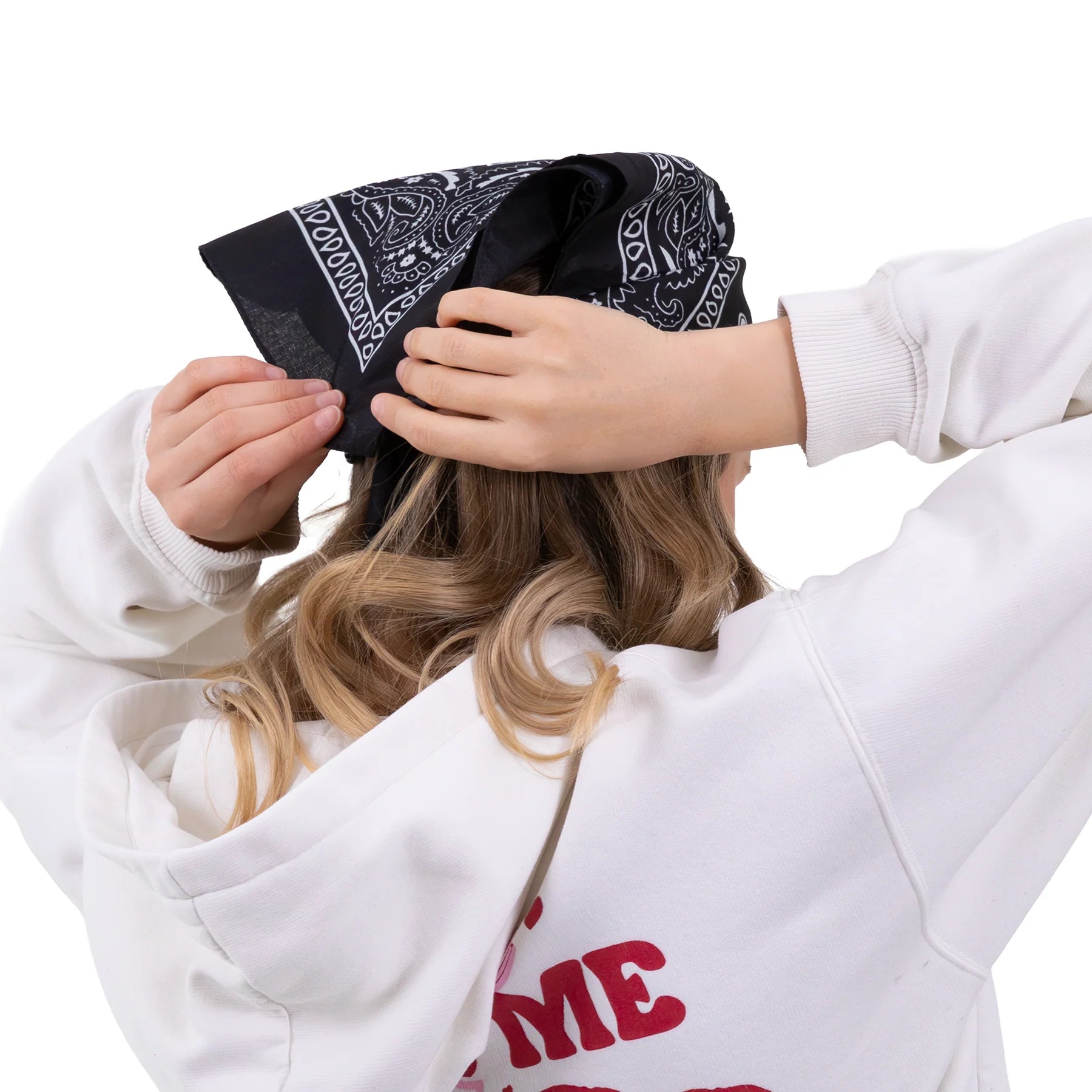 En svart bandana med vitt paisleymönster knyts över håret och visar hur den kan stylas som huvudduk bakifrån.