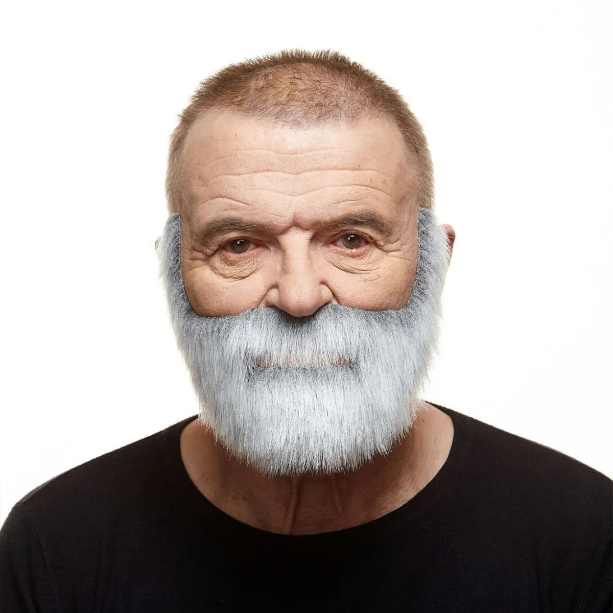  En äldre man med ett leende i blicken bär ett välansat, grått lösskägg och mustasch som ger honom utseendet av en klassisk sjökapten eller fiskare.