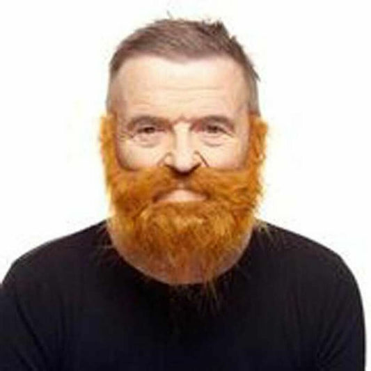 En man med kortklippt hår bär ett stort, vildvuxet orange-rött lösskägg och mustasch som fästs med dubbelhäftande tejp.